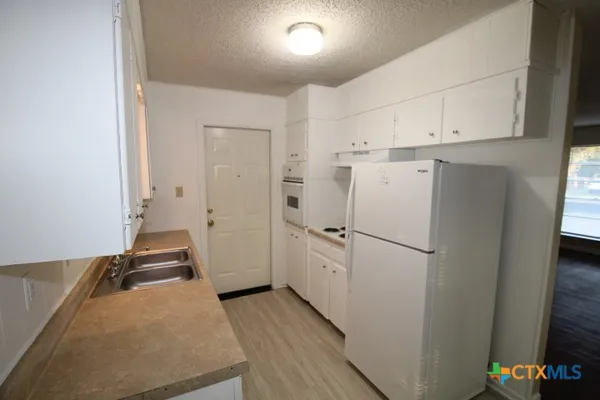a kitchen with white cabinets and white appliances