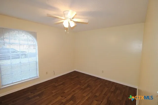 an empty room with wooden floor and fan
