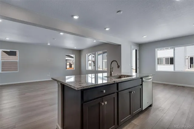 a kitchen with stainless steel appliances granite countertop a sink a refrigerator and wooden floor