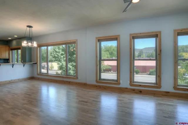 an empty room with wooden floor exposed radiator and windows