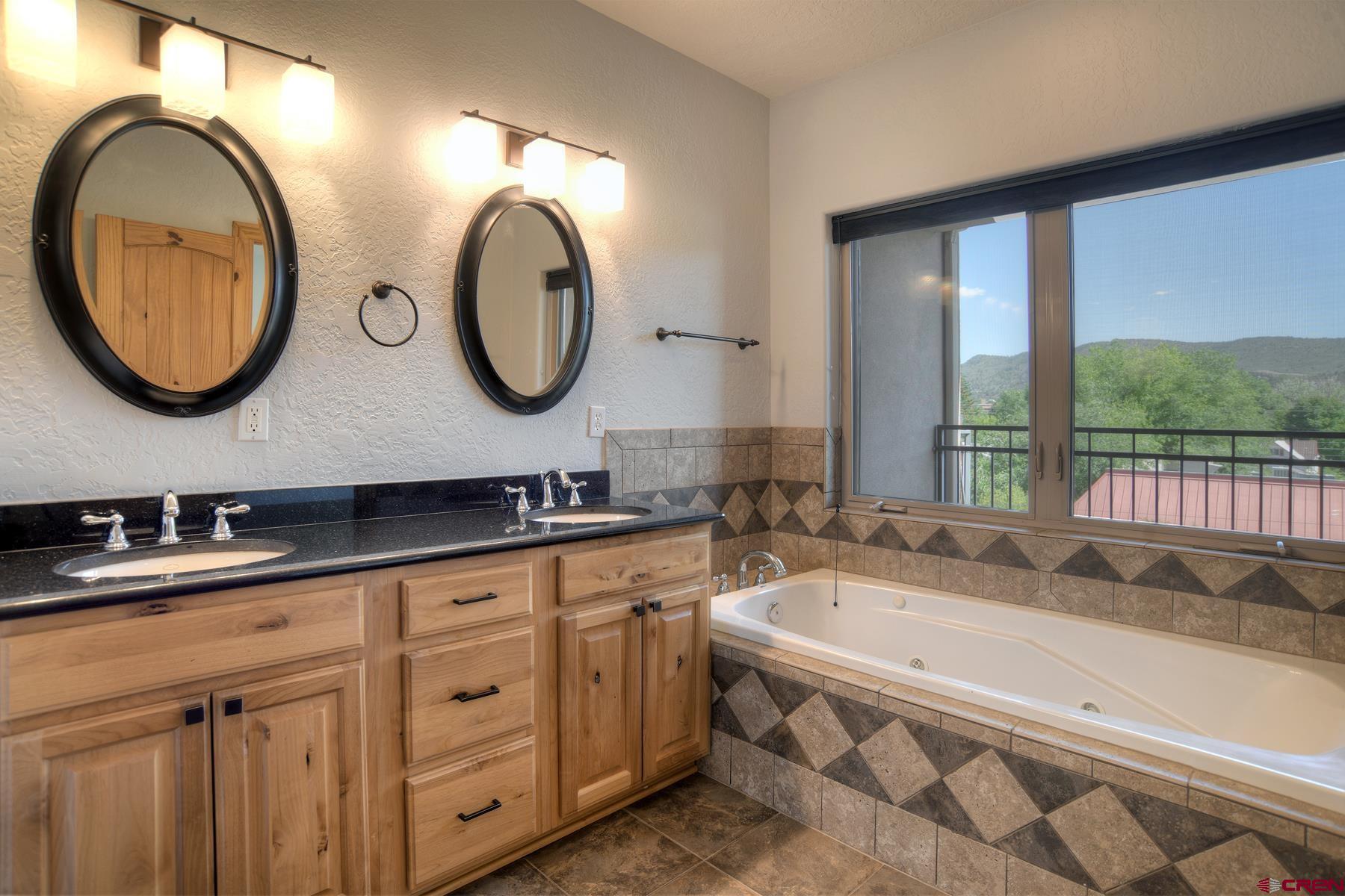 2855 Main Avenue, Unit A204 Durango, CO 81301 - Photo 18 of 45 a bathroom with a granite countertop tub a double vanity sink and a large mirror