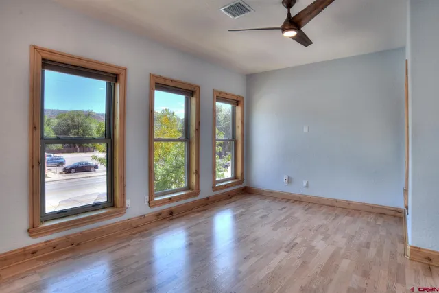 a view of an empty room with wooden floor and a window