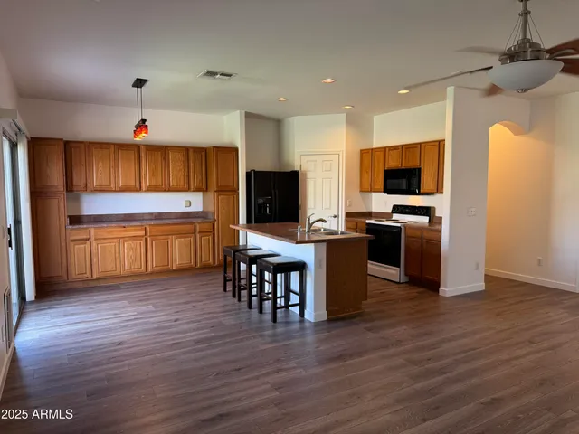 a kitchen with kitchen island granite countertop a stove top oven a sink dishwasher a dining table and chairs with wooden floor