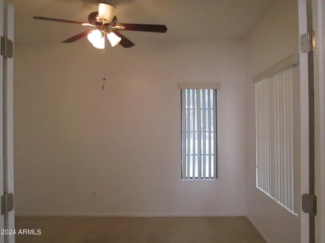 an empty room with windows and fan