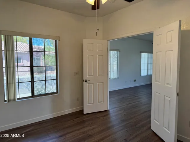 an empty room with wooden floor cabinet and windows