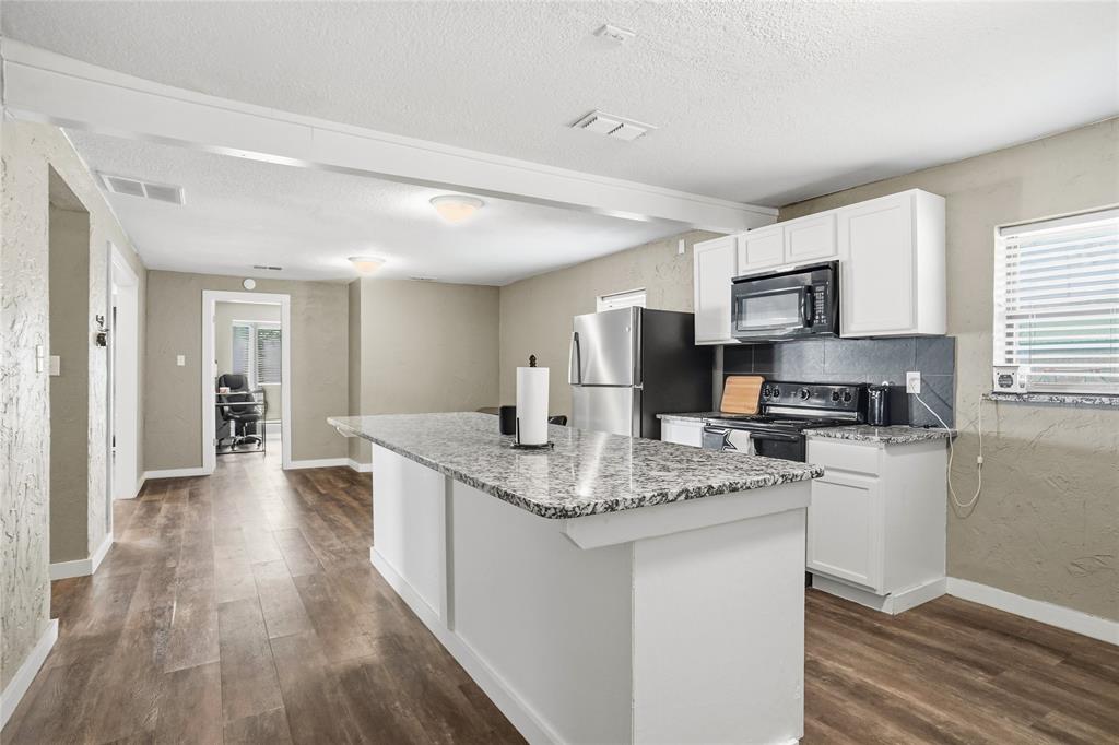 207 School House Road Paradise, TX 76073 - Photo 14 of 33 a kitchen with stainless steel appliances granite countertop a stove top oven a sink dishwasher and a refrigerator with wooden floor