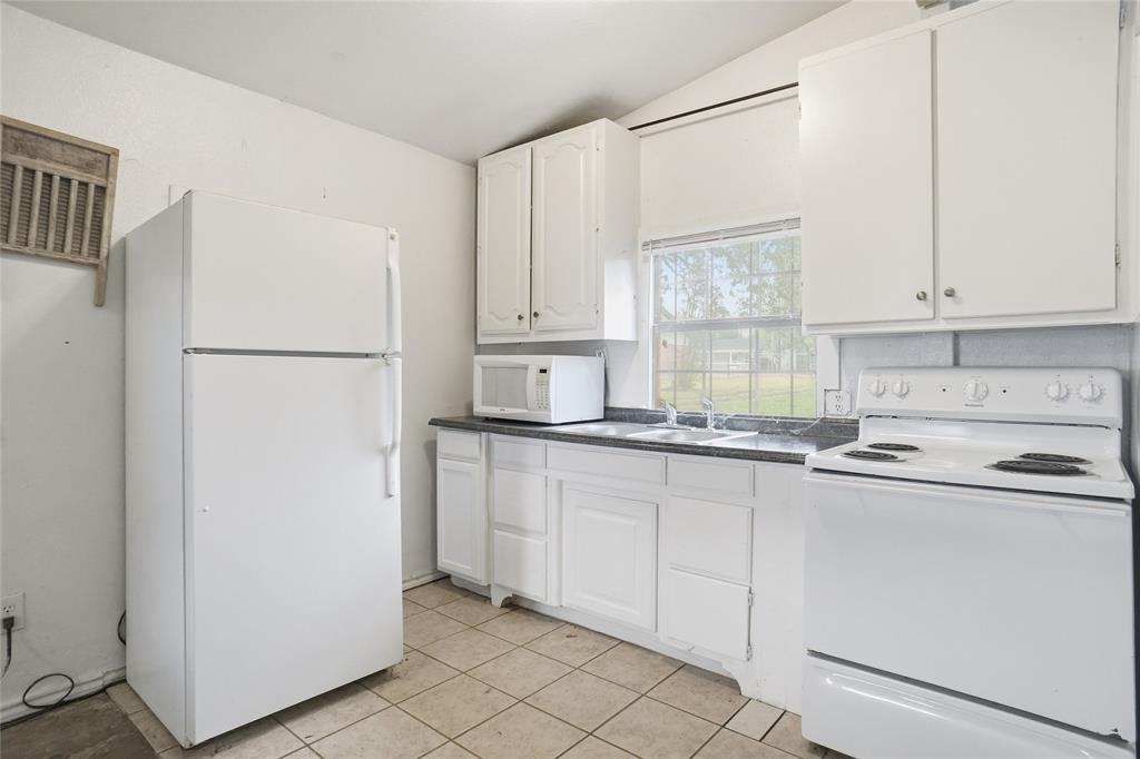 207 School House Road Paradise, TX 76073 - Photo 27 of 33 a kitchen with granite countertop white cabinets and refrigerator