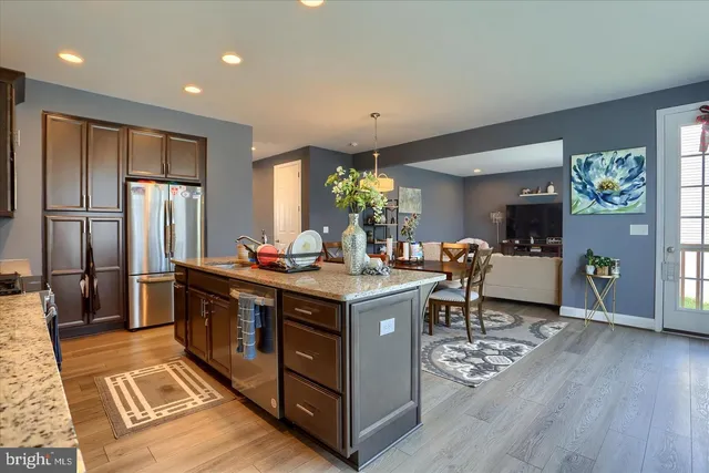 a living room with stainless steel appliances granite countertop furniture wooden floor and a view of kitchen