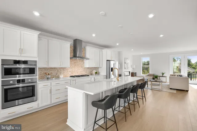 a large kitchen with kitchen island a dining table chairs and white cabinets