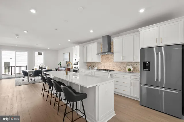 a kitchen with stainless steel appliances a dining table chairs stove refrigerator and cabinets