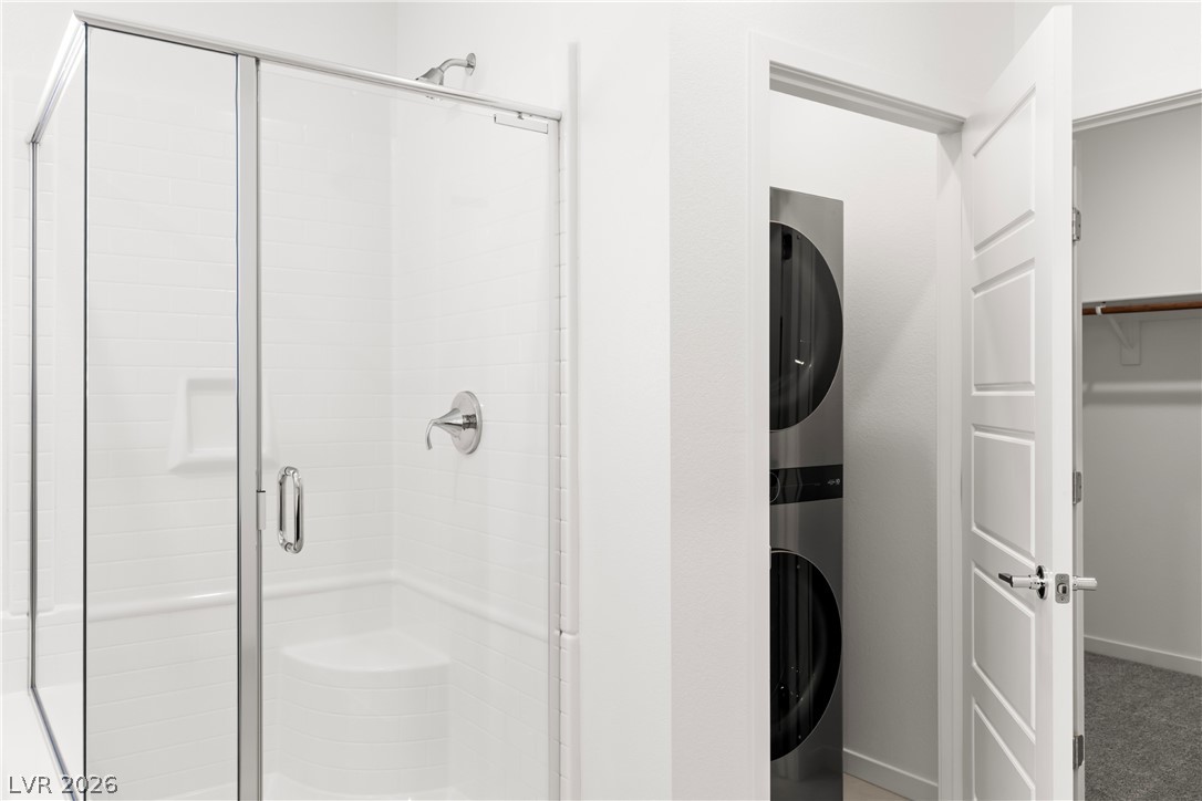 320 Isla Enclave Way Henderson, NV 89011 - Photo 15 of 49 This clean and bright bathroom features a modern glass-enclosed shower alongside convenient stacked laundry facilities.