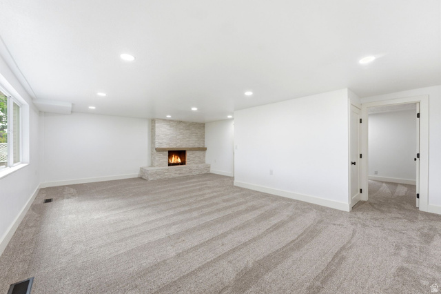 871 Bonita Way Centerville, UT 84014 - Photo 25 of 61 Spacious room featuring a stone-clad fireplace with a wood mantel, soft grey carpeting, recessed lighting, and white trim