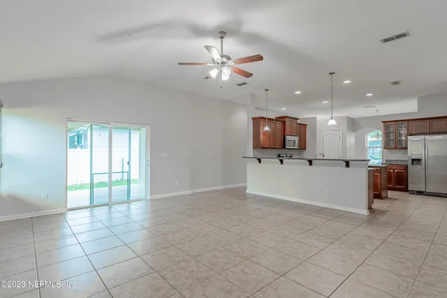 a view of an empty room and kitchen with furniture and a window