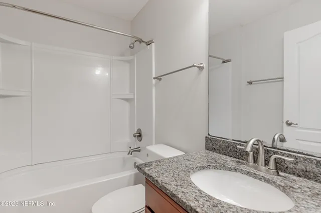 a bathroom with a granite countertop sink mirror toilet and bathtub