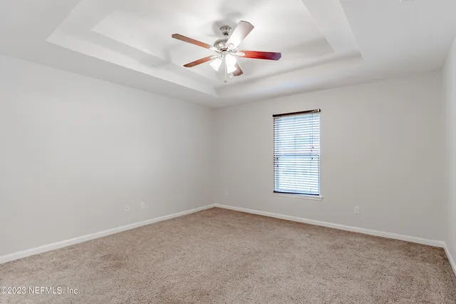an empty room with chandelier fan and windows