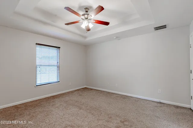 an empty room with a window and a ceiling fan