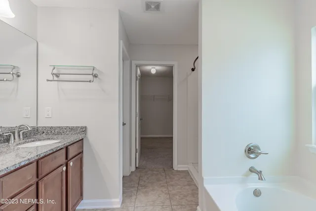 a bathroom with a granite countertop sink and a bathtub