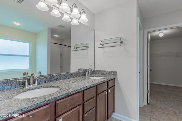 a bathroom with a granite countertop double vanity and a mirror