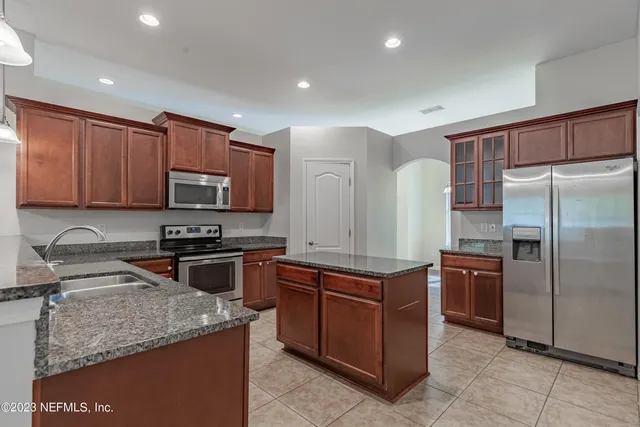 a kitchen with stainless steel appliances granite countertop a stove top oven a refrigerator and a sink