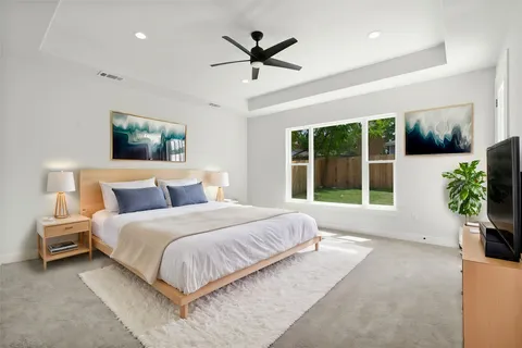 a spacious bedroom with a large bed a chandelier and a large window