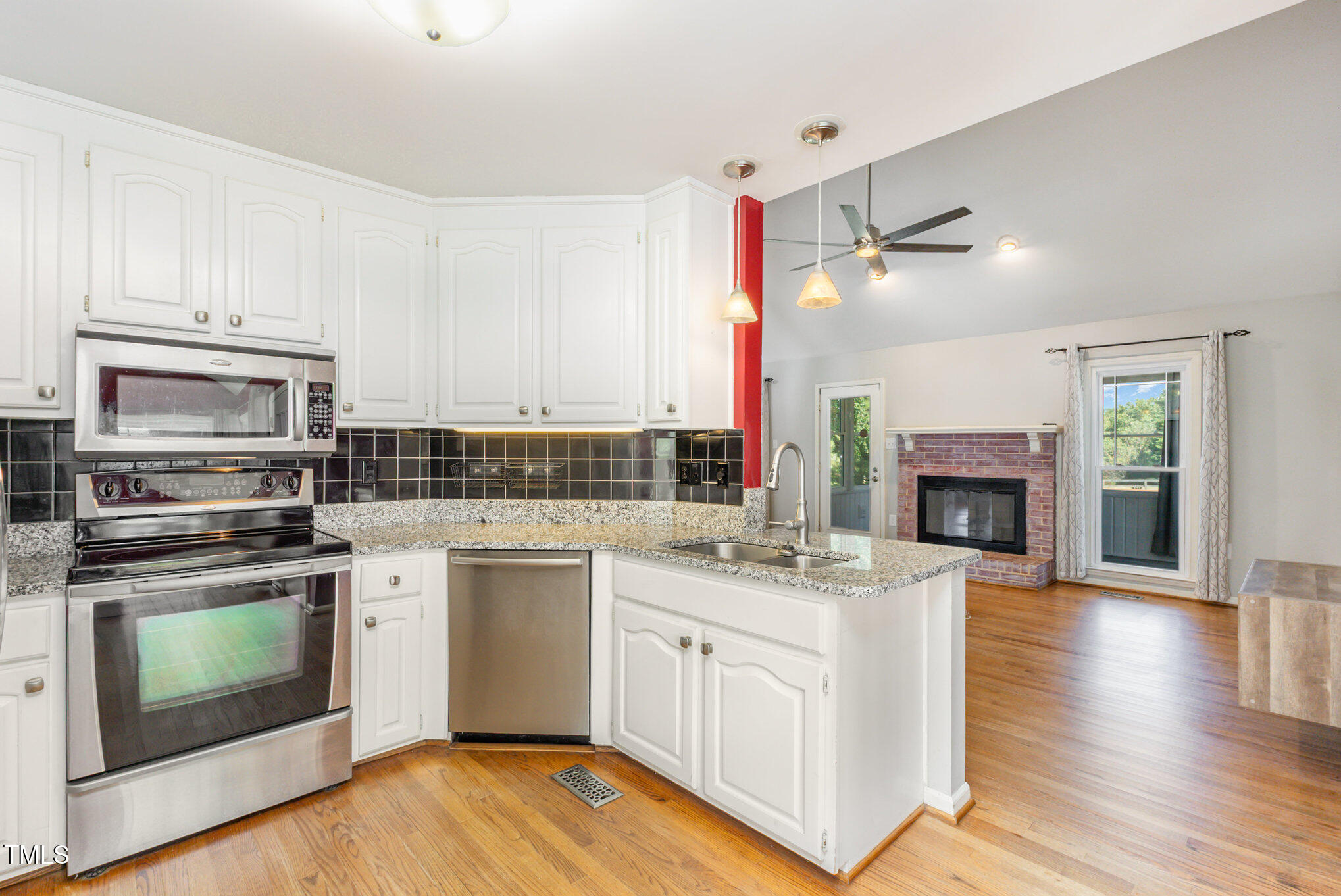 823 Shadow Lake Drive Willow Spring, NC 27592 - Photo 11 of 31 a kitchen with white cabinets stainless steel appliances and wooden floor