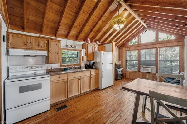 a kitchen with stainless steel appliances granite countertop a stove a refrigerator a microwave oven with a dining table and chairs with wooden floor