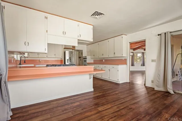 a view of kitchen with stainless steel appliances granite countertop a stove top oven and a refrigerator with wooden floors