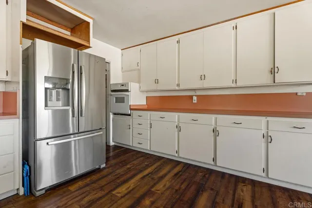 a kitchen with stainless steel appliances white cabinets and wooden floors