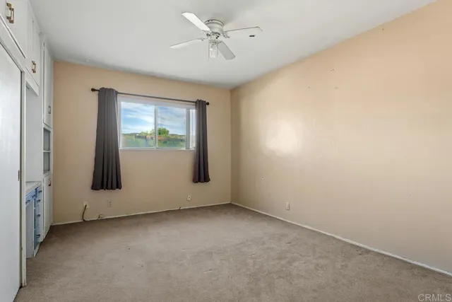 an empty room with windows and fan