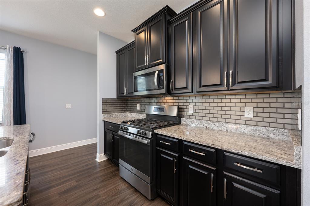 1398 Riley Circle Deland, FL 32724 - Photo 4 of 29 a kitchen with granite countertop stainless steel appliances and wooden cabinets