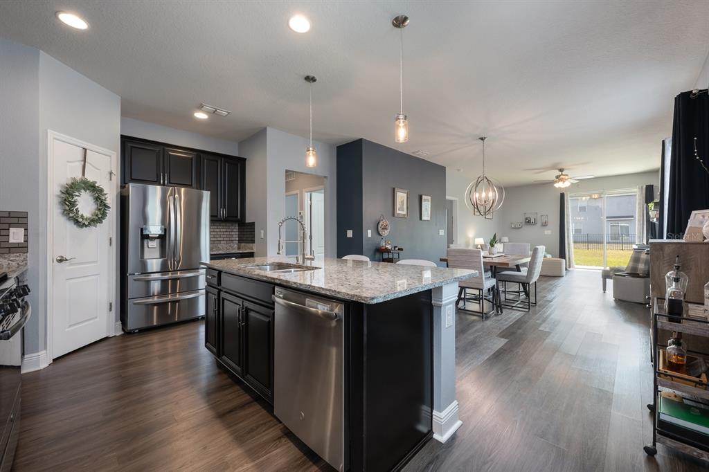 1398 Riley Circle Deland, FL 32724 - Photo 5 of 29 a kitchen with stainless steel appliances granite countertop a refrigerator a sink dishwasher a stove and a dining table with wooden floor