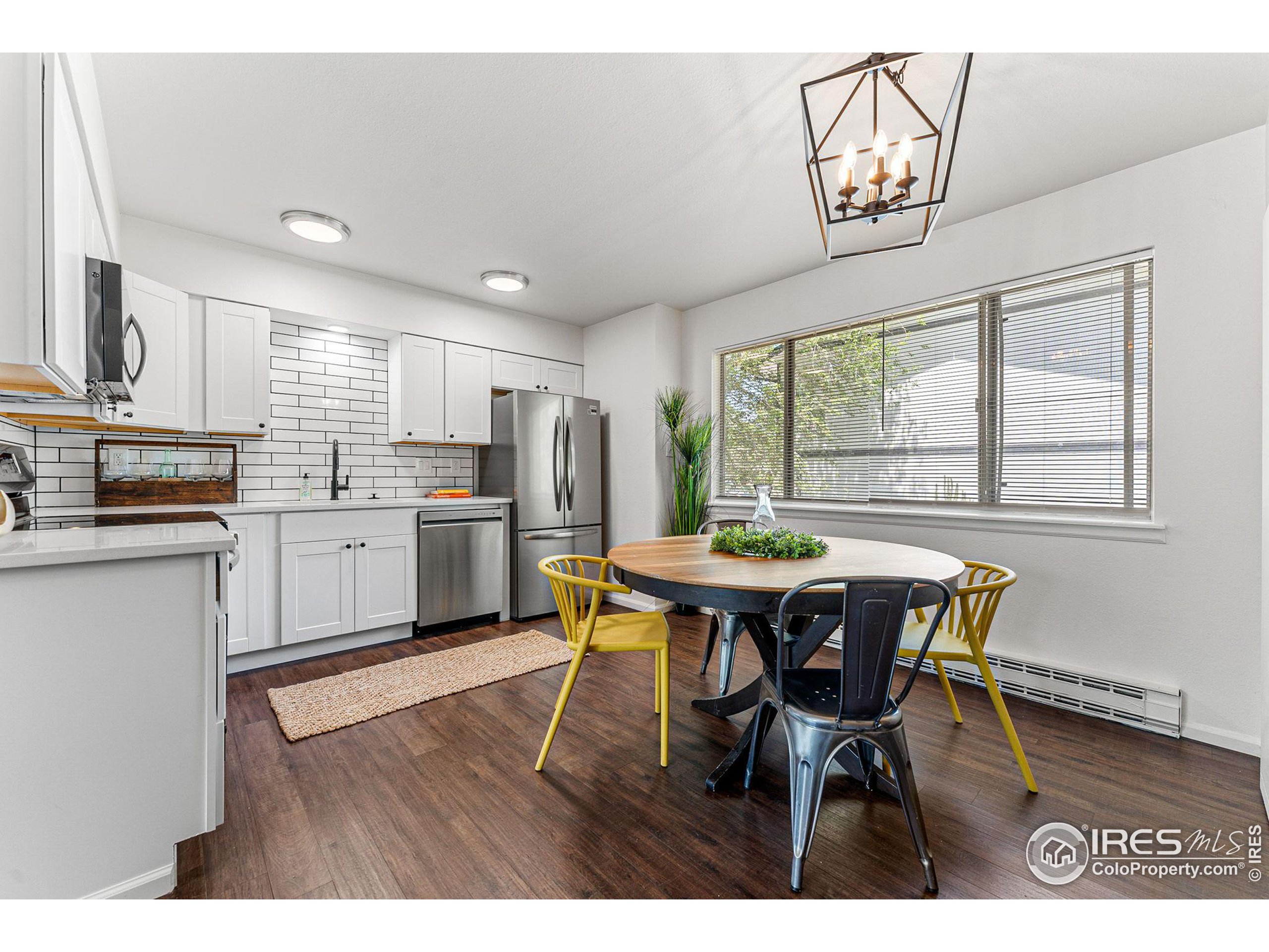 2408 Orchard Place Fort Collins, CO 80521 - Photo 11 of 36 a open kitchen with stainless steel appliances kitchen island granite countertop a table chairs sink and cabinets