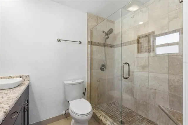a bathroom with a granite countertop sink a toilet and shower