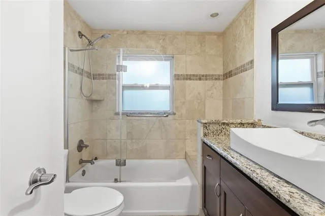 a bathroom with a granite countertop sink a toilet and shower