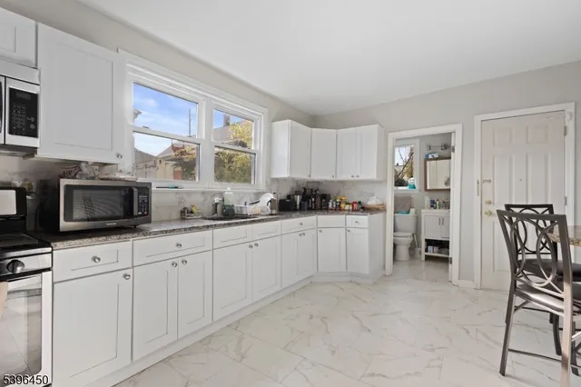 a kitchen with granite countertop white cabinets a window and stainless steel appliances