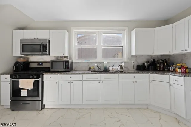 a kitchen with white cabinets a window and stainless steel appliances