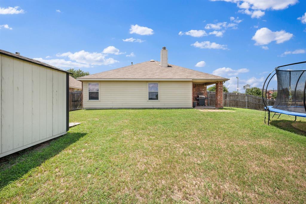 14152 Rodeo Daze Drive Fort Worth, TX 76052 - Photo 20 of 20 Spacious backyard with a covered patio featuring brick columns, a wood fence perimeter, and a detached storage shed