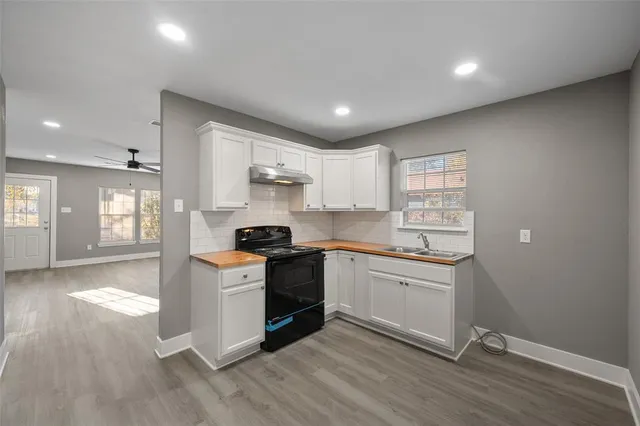 a kitchen with granite countertop a stove top oven sink and cabinets