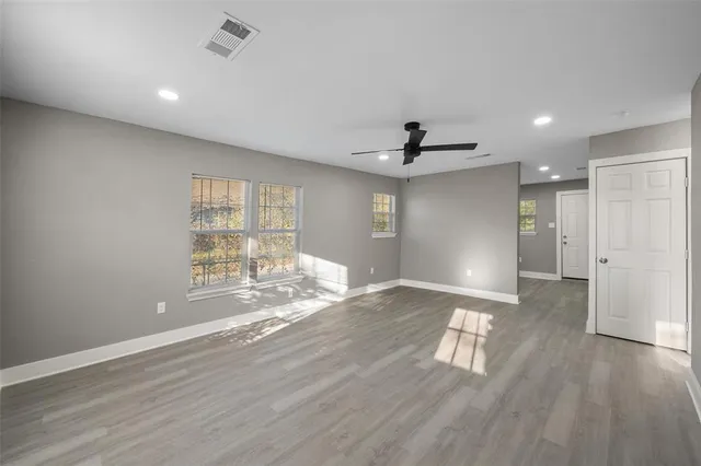 a view of empty room with wooden floor and fan
