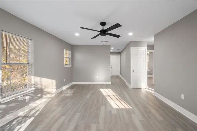 a view of empty room with wooden floor and fan
