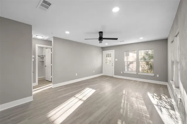 a view of an empty room with a window and wooden floor
