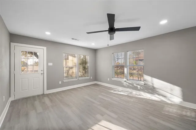 a view of empty room with wooden floor and fan
