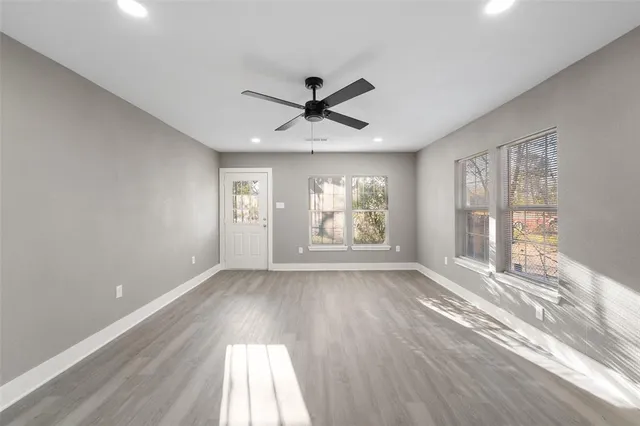 a view of an empty room with a window and wooden floor