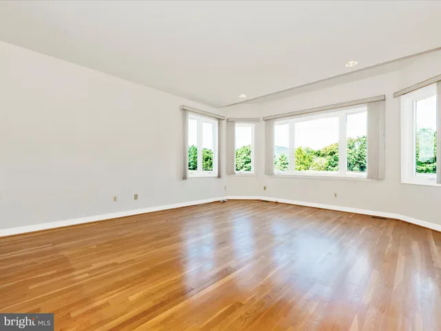 a view of an empty room with window and wooden floor