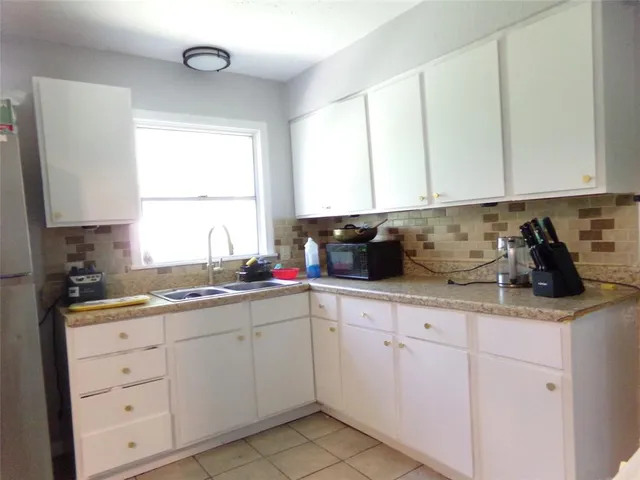 a kitchen with white cabinets and sink