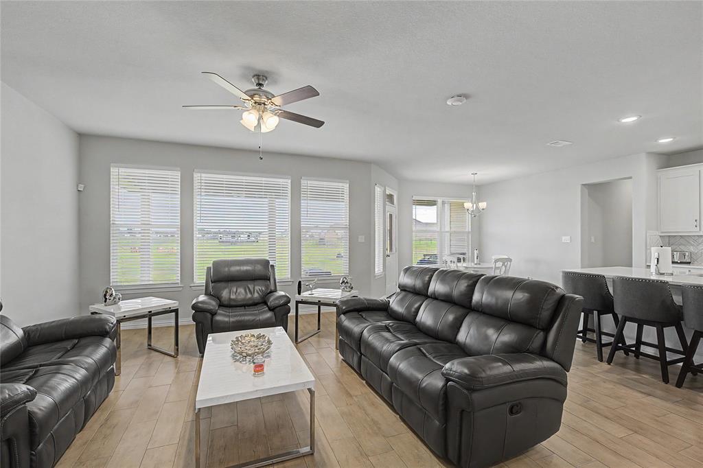 185 Chester Road Springtown, TX 76082 - Photo 15 of 40 Open-concept living area featuring a ceiling fan with integrated lighting, wood-finish flooring, and white window blinds