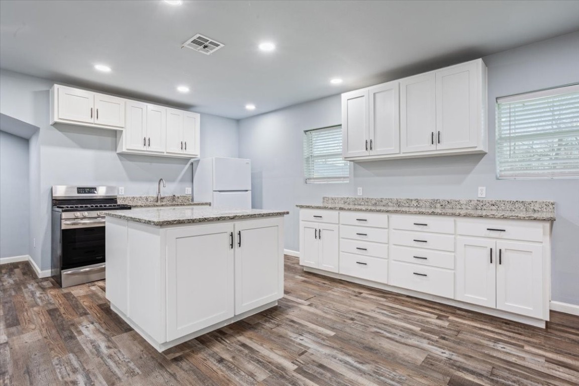 a kitchen with granite countertop white cabinets white stainless steel appliances with a sink and dishwasher