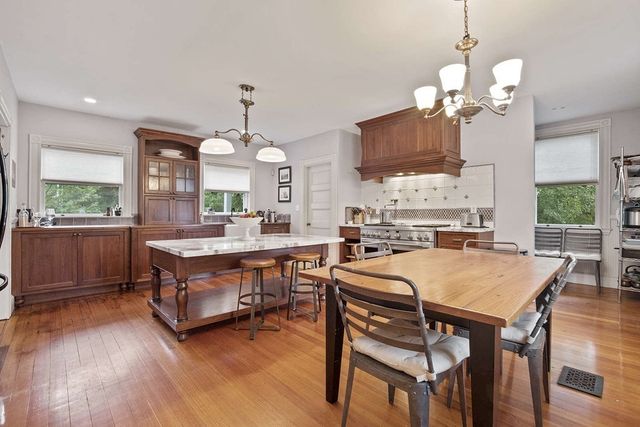 a kitchen with a stove center island a sink cabinets and wooden floor