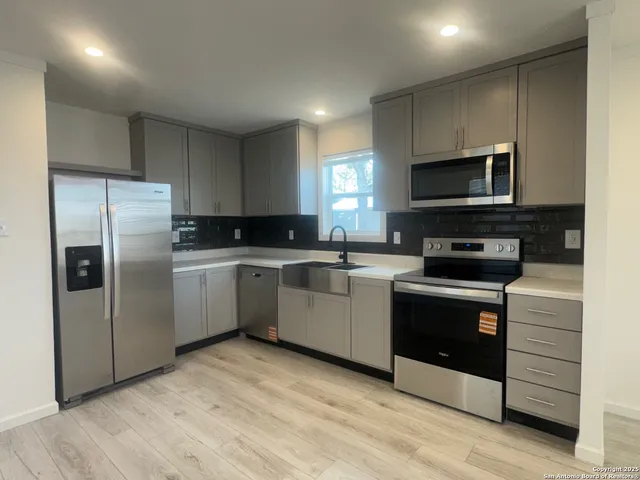 a kitchen with granite countertop a refrigerator and a stove top oven