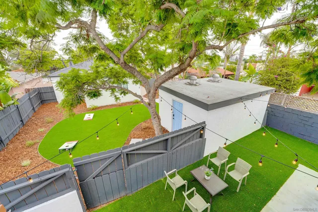 a view of a backyard with table and chairs potted plants and wooden fence